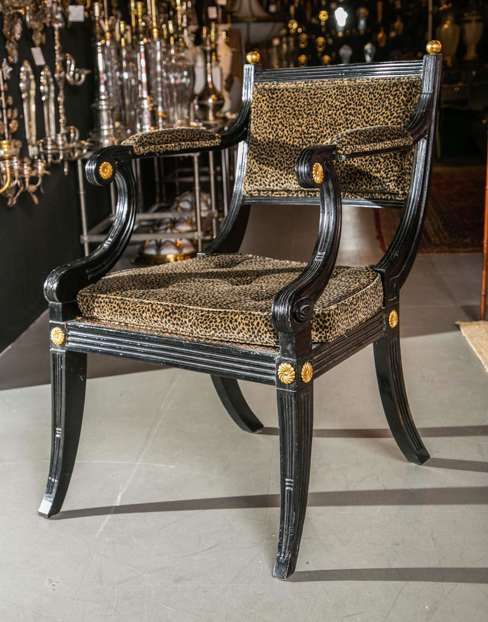 A pair of English regency klismos chairs. Black with brass rosettes and gilt wood ball finials.