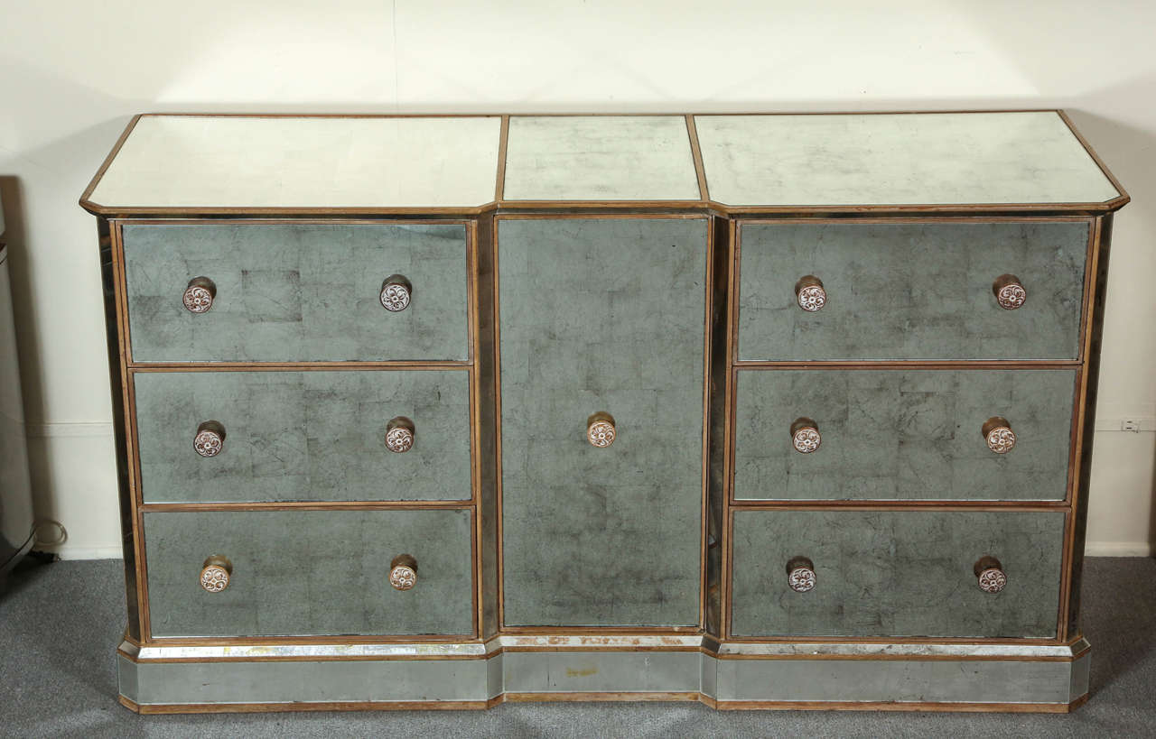 This Gorgeous reverse silver leafed mirrored cabinet is absolutely
stunning from every angle. The cabinet has wood trim  and matching
carved floral pulls.