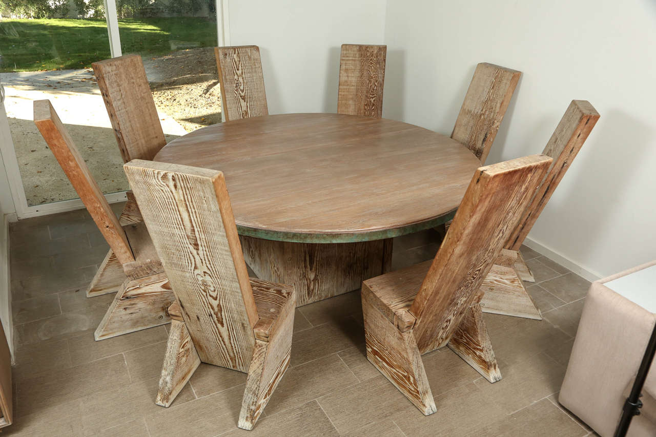 Phenomenal dining set which includes a massive dining table and eight matching chairs. The chairs and table base are constructed from thick slabs of solid wood. The wooden surfaces are sandblasted and unfinished. The table top has been sanded smooth