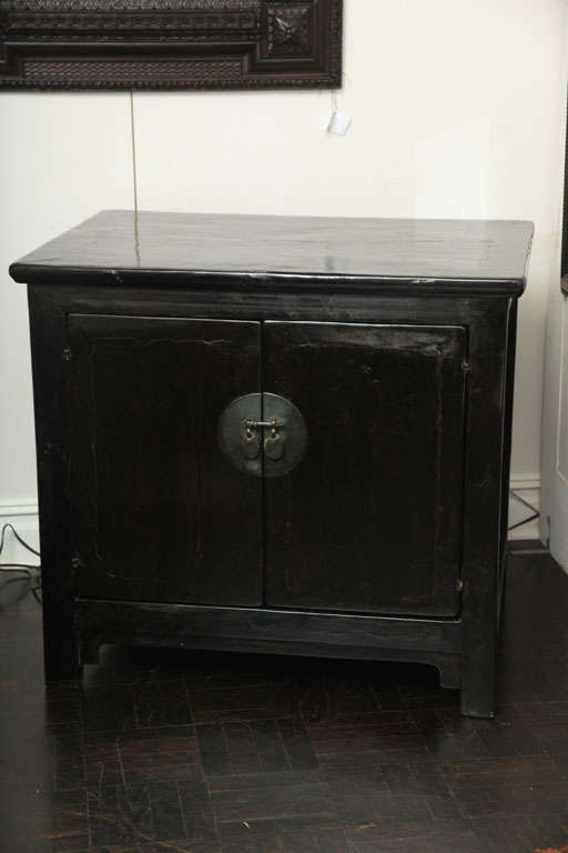 19th century black lacquer cabinet. Two doors with bronze escutcheons, molded top, square legs.