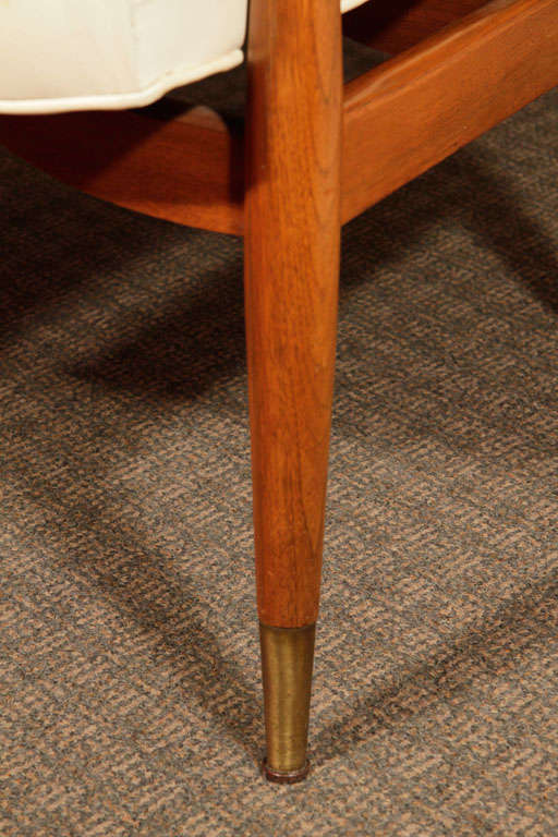 A pair of Mid Century Modern Arm Chairs have graceful curvalinear cherry frames with the look of Scandinavian design from the Mid Century period. The seats and backrests are upholstered in the original creme leather. Brass nailheads and button