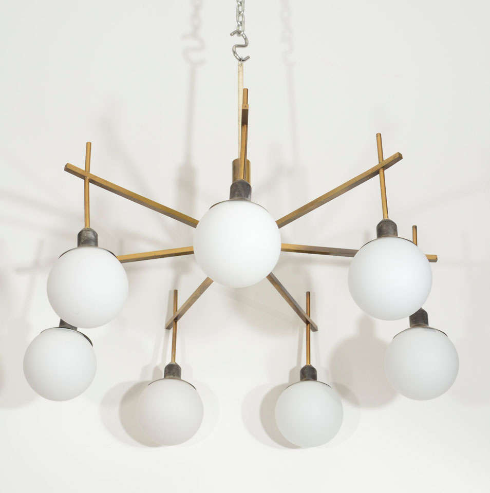 Seven white globes hang from the brass arms of this interesting chandelier.