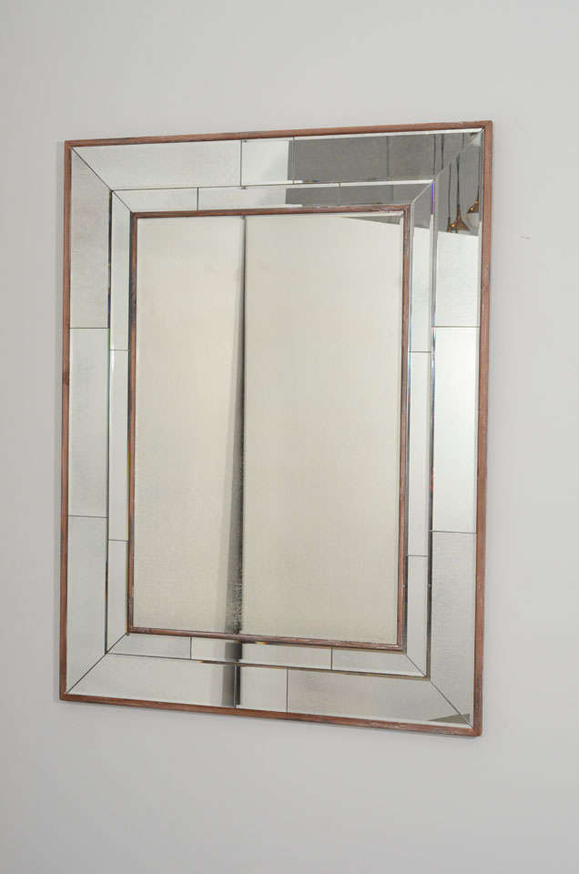 A wooden frame wraps around this rectangular mirror. Constructed with one large mirror at the centre and smaller pieces placed around it. A Classic piece.