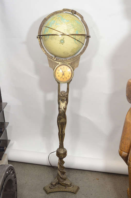 We have never seen anything quite like this globe. It has Art Deco influence as well as a neoclassical serpent base. The metal we believe to be a base metal with gilt patina. The clock in the middle which works , just makes this a perfect