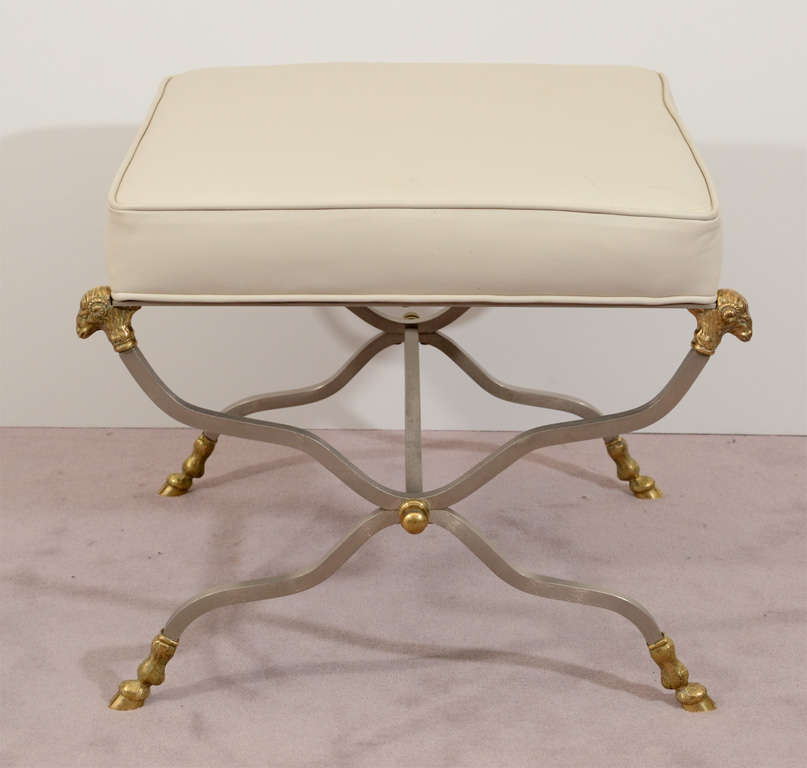 A pair of vintage white leather stools or benches with nickeled bronze x-form bases adorned with gilt bronze ram's heads at each corner and 