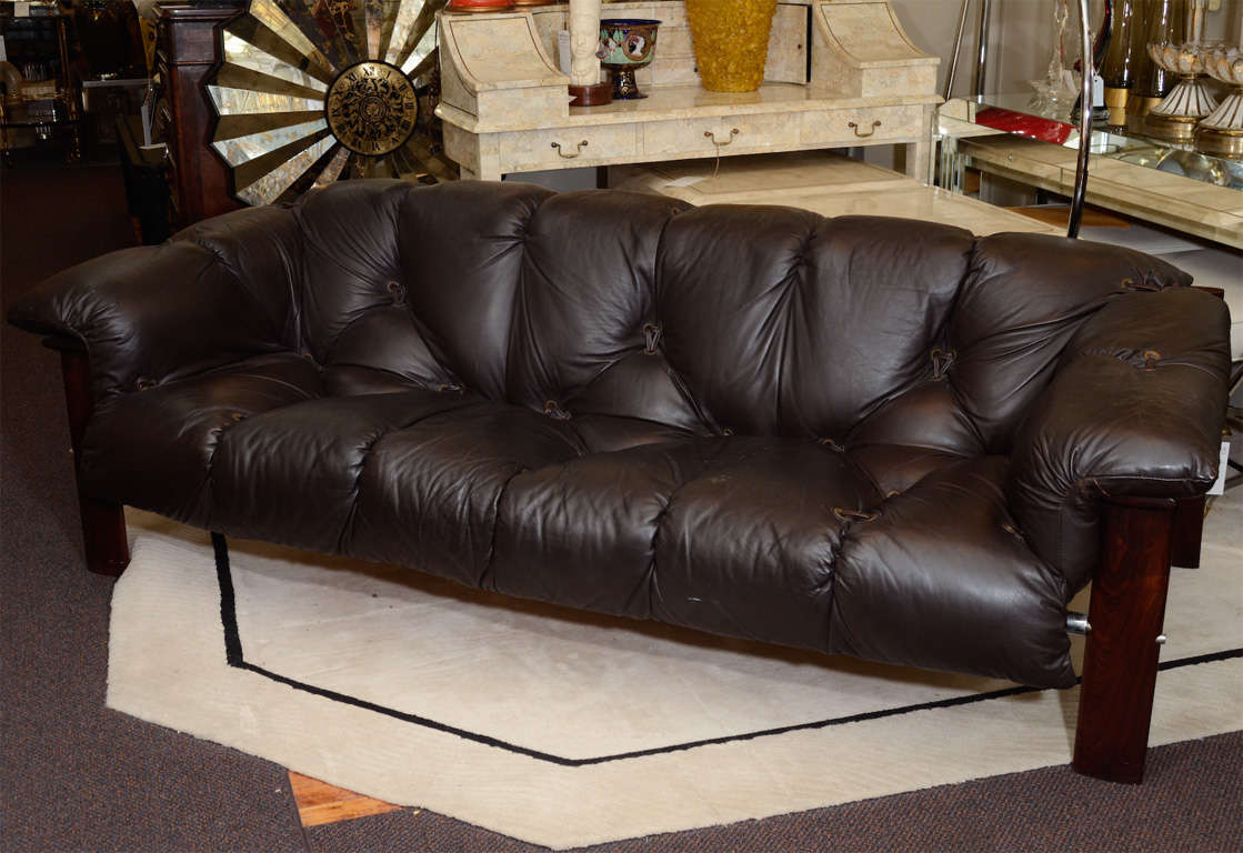 A vintage couch in brown leather with wooden frame. The piece is by Percival Lafer and retains its original hang tag as well as its label on the frame. It is in good vintage condition with age appropriate wear; some small white speckling on one arm;