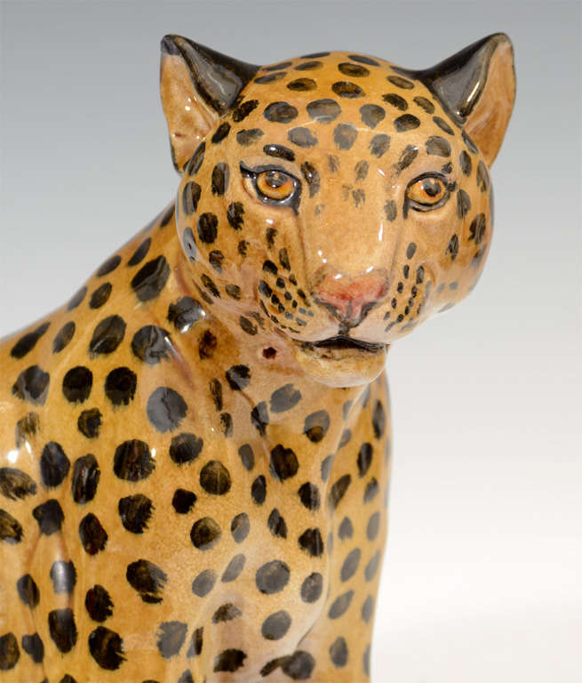 A vintage ceramic majolica sculpture of a sitting leopard. The piece is stamped 