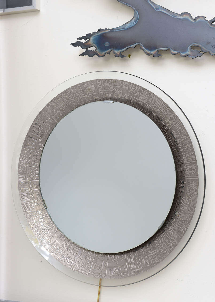 Miroir rond en cristal avec motifs gravés au jet de sable et plaqué argent.
Le miroir est doté d'un rétroéclairage. Signé M. A&M.