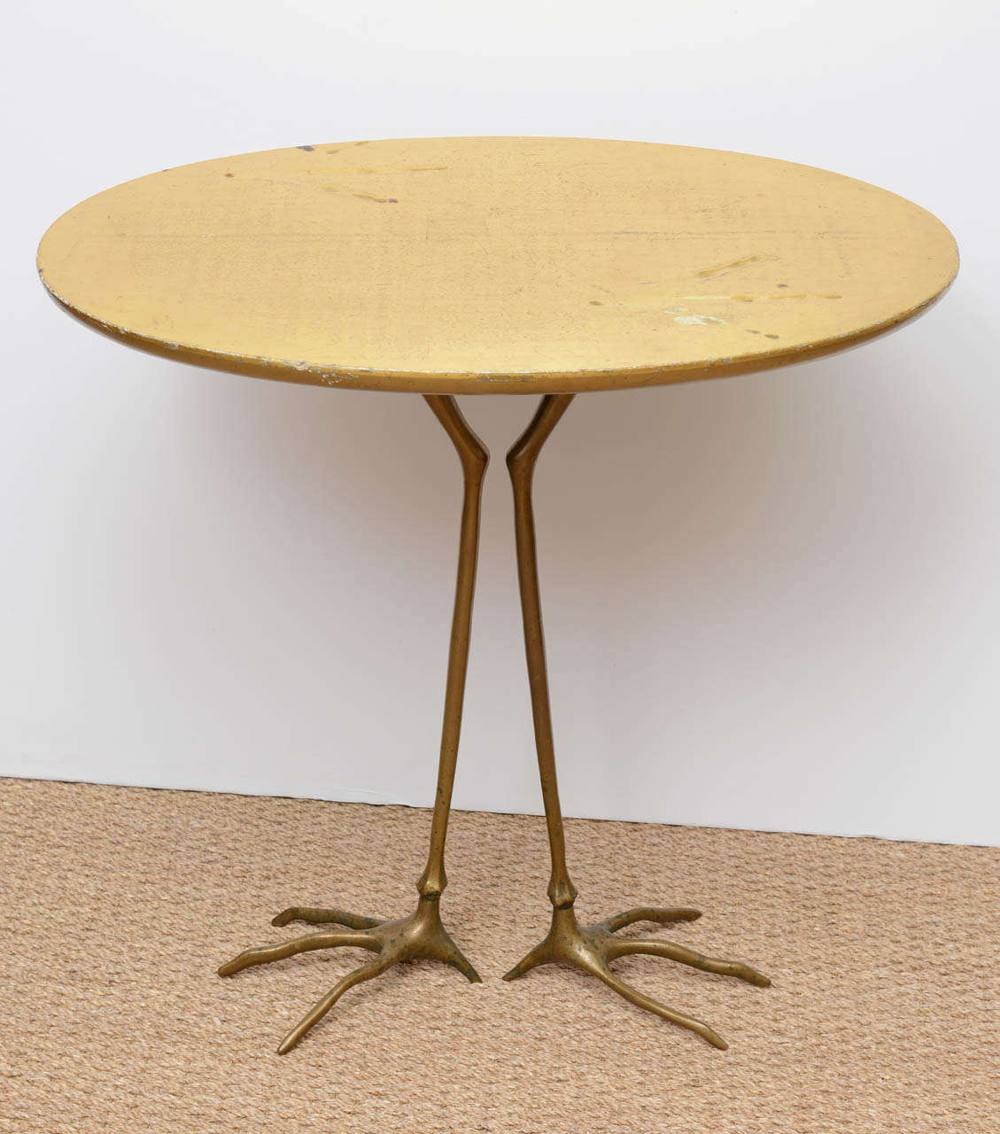 Pedestal table "Traccia" by the Swiss designer Meret Oppenheim.
An oval shaped, gold giltwood top featuring bird footprints, on top of cast bronze chicken legs.
Design originally from 1939 and manufactured by Dino Gavina in 1972.