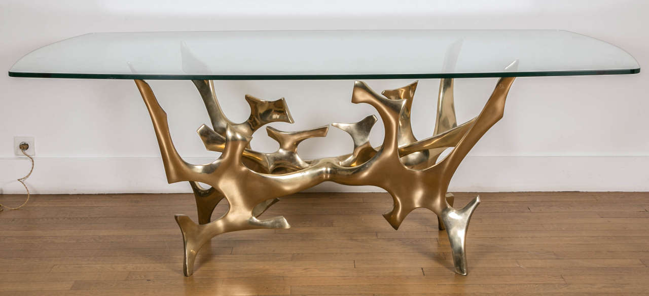 Important gilt polished bronze sculpture as a large table by Fred Brouard, 1970s, with an oblong glass top.
Signed.
Measures: Base: H 71.5 x L 103 x D 59 cm.

Fred Brouard (1944-1999), met Alicia Penalba and Henri Georges Adam then he worked