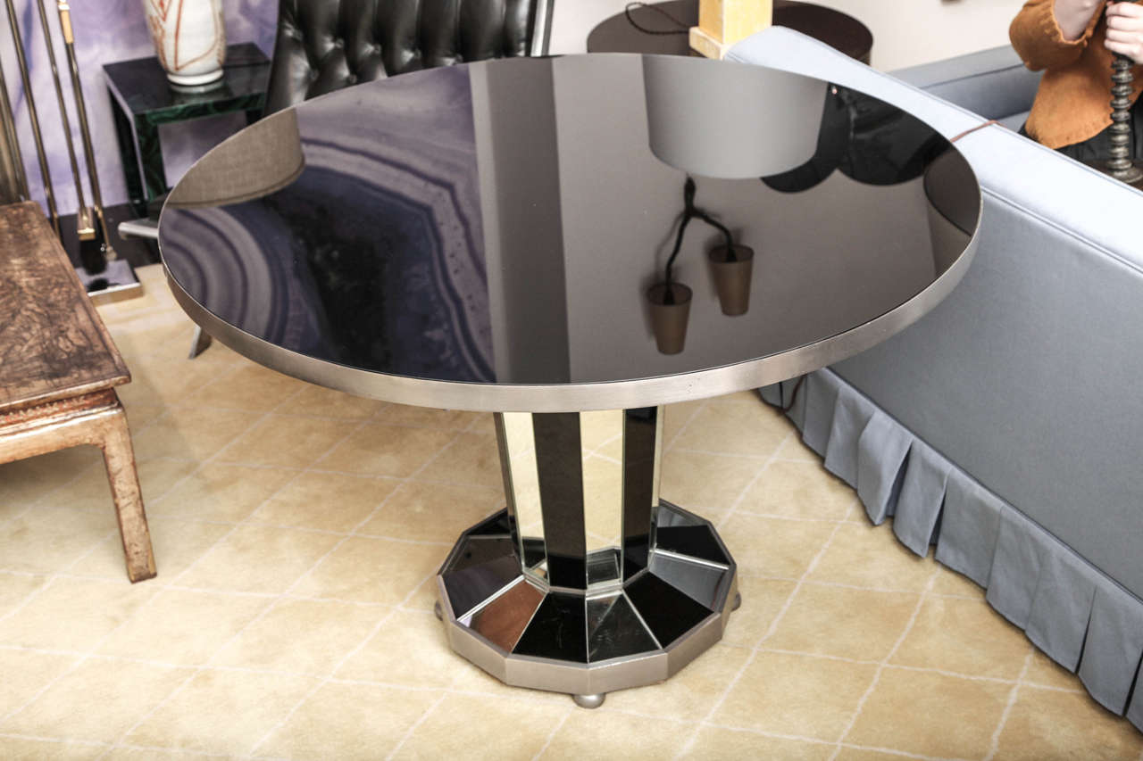 Center table raised on a pedestal base in nickel with mirror and black glass.
French, 1937.