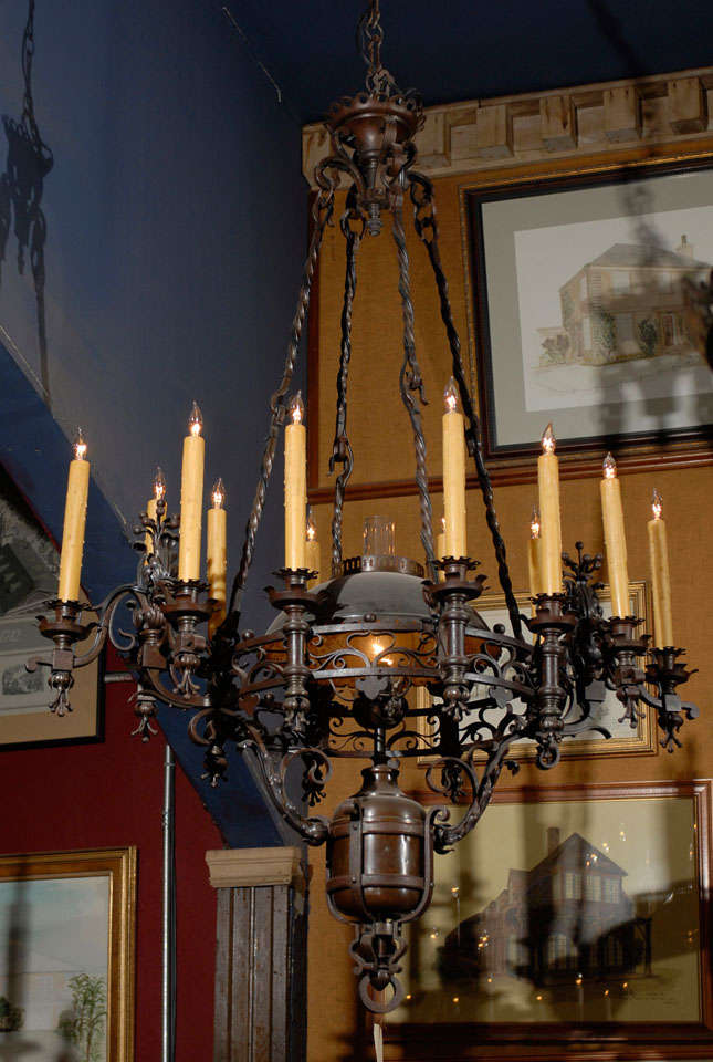 The light fixture with an electrified former oil lamp,complete with original copper oil font ,shade and glass chimney surrounded by a circular pierced gallery ,supporting brackets with triple candles between single candle holders, giving a total of