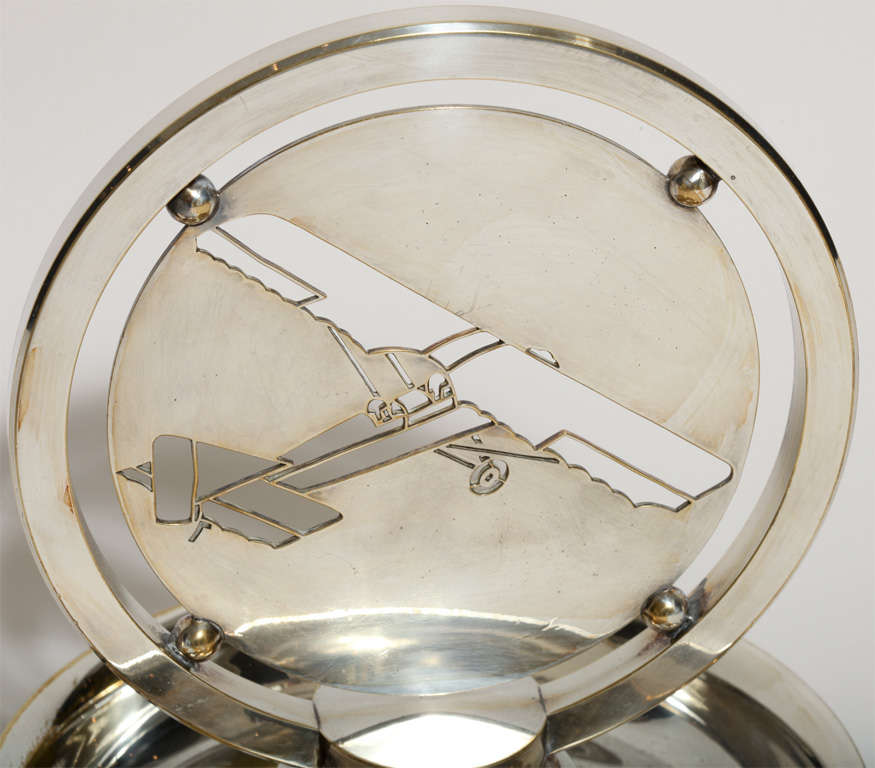 Silver plated vide poche with mounted cut-out design of two-seater monoplane by Gustave Keller Fre`res (1881-1922), Paris.
Hallmarks: G. Keller Freres/ the cut-out design signed DB.