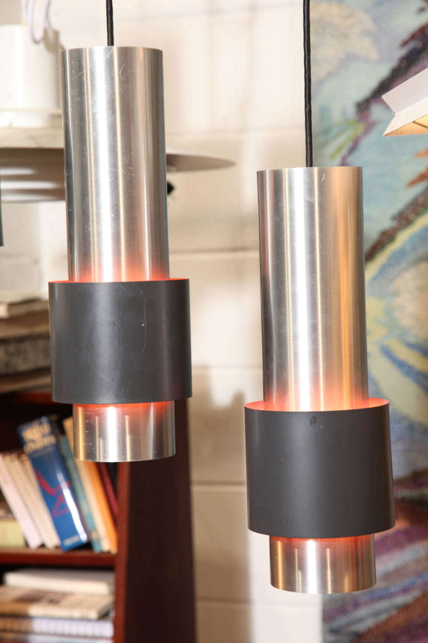 1960's Danish Modern stainless steel pendant lamps.  Features a cylindrical design with a painted black ring.  Interior is painted light red/pink.

4 available at $750 each.