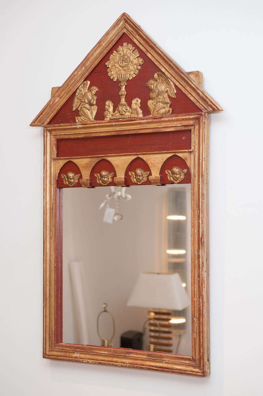 A charming antique ecclesiastical frame with warm red and gold tones with new mirror.