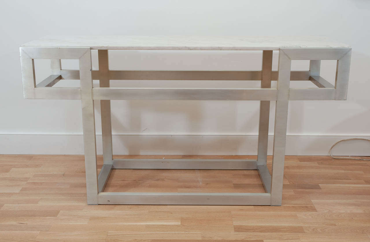 A  geometric designed brushed metal
console with a soft carrera marble top.