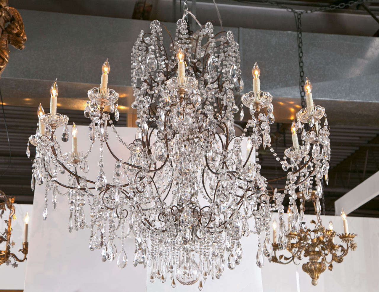 An Italian 12 light grand ballroom crystal chandelier with a carved and gilt center shaft and shaped iron arms. Retains most of its original crystal. Newly rewired.