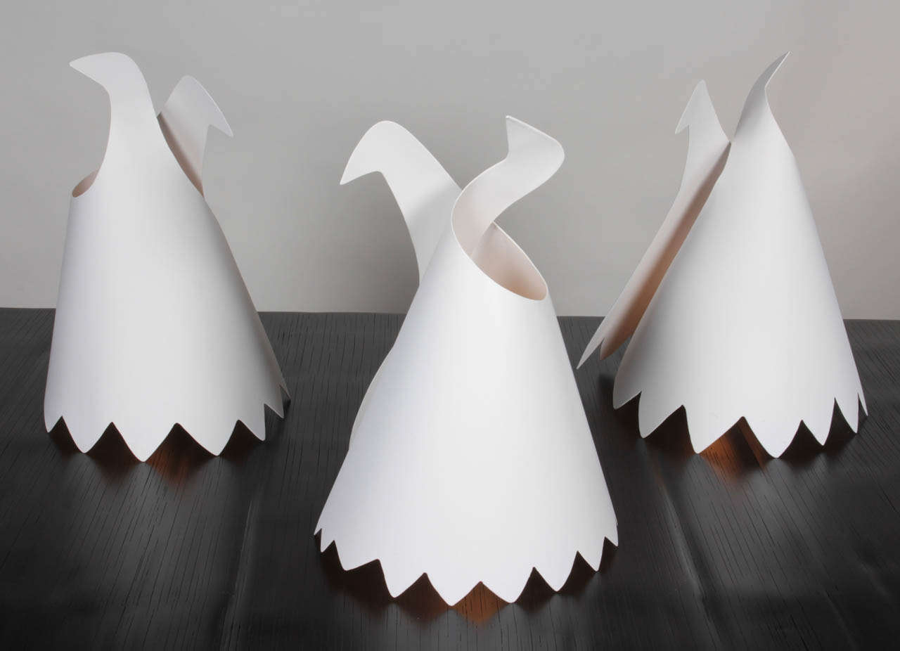 Molded in white painted metal these table lamps cast beautiful rays of light like coddling doves or dancers in the night. The subtle glow warms any interior and the abstracted form lets the imagination soar. Signed by the artist as part of the 2013