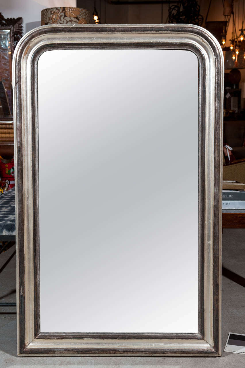 Period Louis Phillippe mirror in typical 19th century restrained style .
20th century updated silver leaf and ebonized finish.  Not recent but would not have been the original finish of that period.