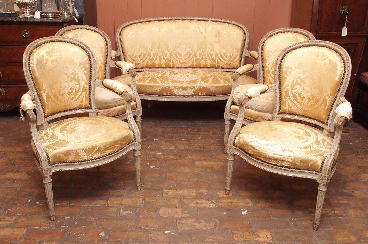 19th century French painted salon set with carved decoration in the Louis XVI taste, with canape and four fauteuils.