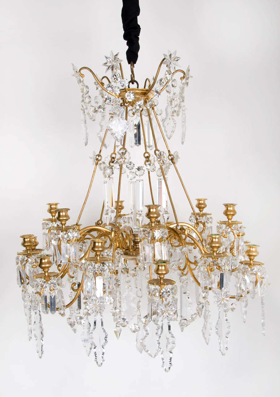 A mid 19th century French ormolu and crystal 18 light Chandelier by Baccarat, around 1850.  A central receiver plate issuing twelve arms on which hang moulded crystal pendants and chains of octogonal drops. On six of the arms is constructed a fixing