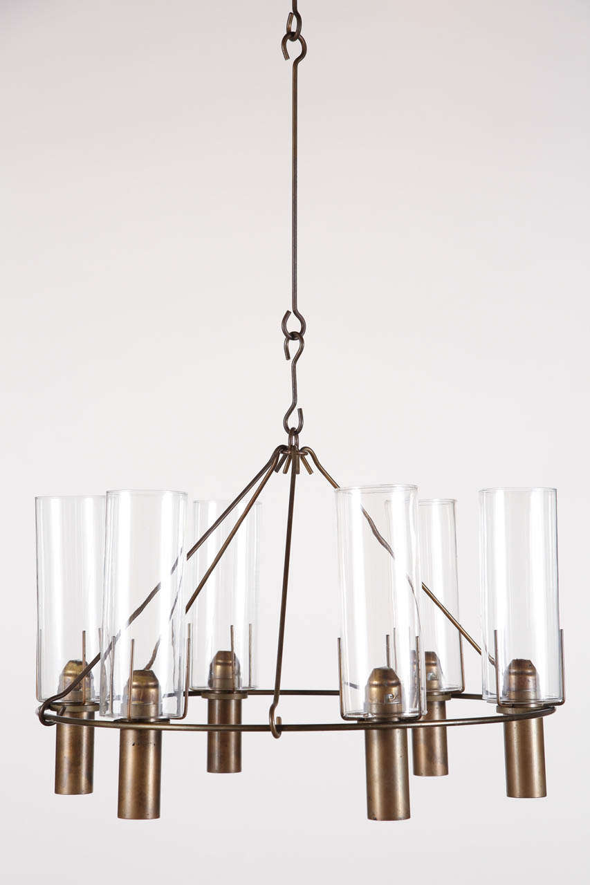 Hanging bronze and glass candelabra by Stuart Barnes for Robert Long, Inc. As featured in California Design '76.
The chandelier involves innovative, spring-loaded canisters to house each candle - when lit, only the flame is visible and the candle