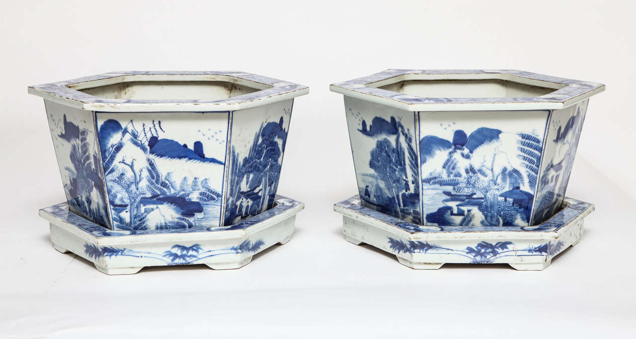 Pair of Chinese blue and white porcelain hexagonal jardinieres on stands, 19th century. Idyllic scenes of a lake side retreat with towering mountains, serene fishermen, and contemplative scholars.