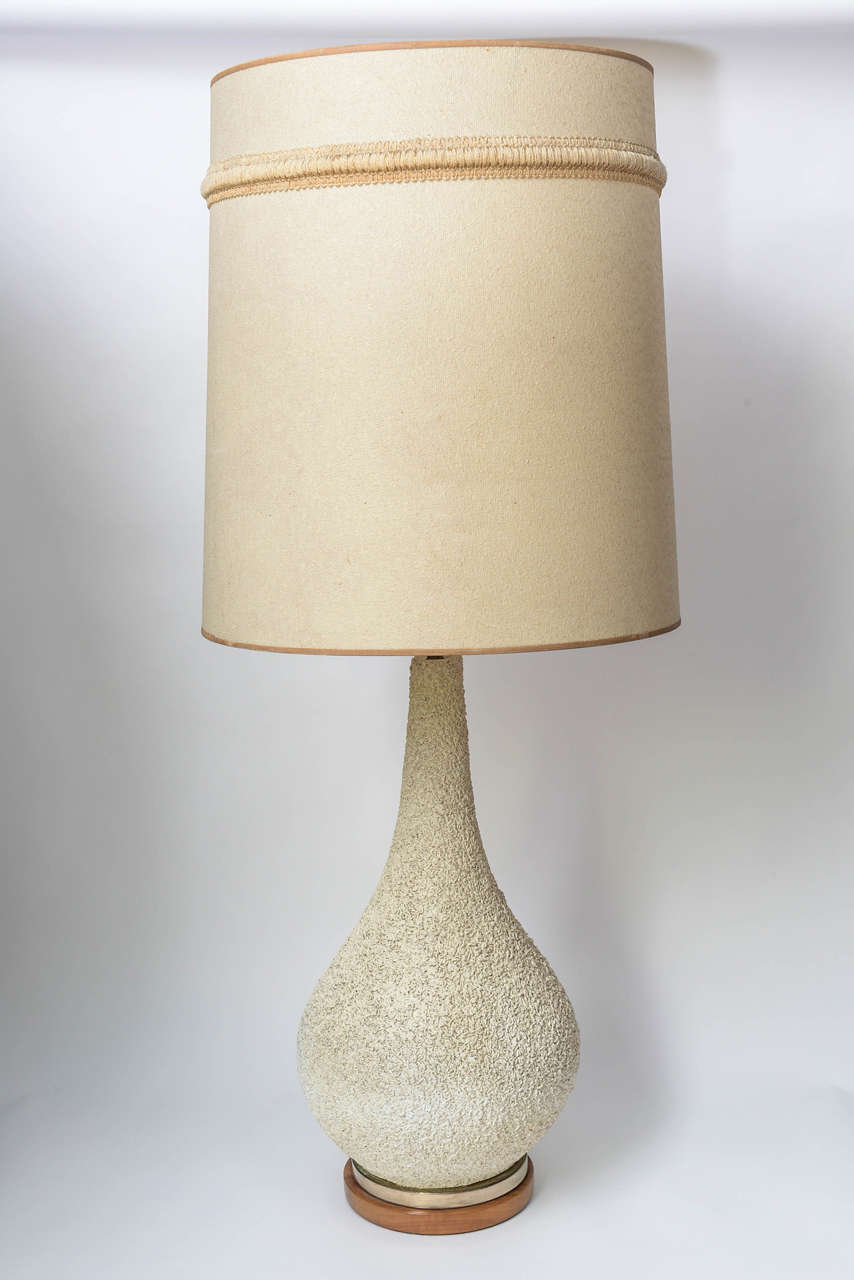 Beautiful and tall pair of statement-maker, this 1960s Mid-Century Modern Danish style Ceramic/Pottery textured off white ceramic lamps seated upon a brass and Teak are the perfect accent for any room. Original embroidered shades are included. Total