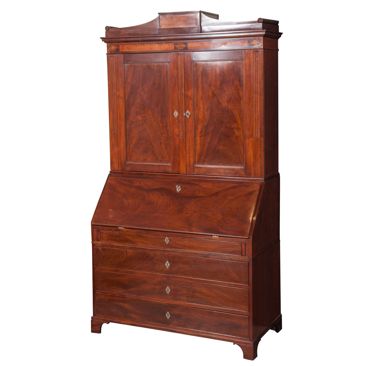 Pregevole secretaire danese Luigi XVI in mogano e legno di frutto, 1780-1790 circa, in tre parti: il piano con cornice a volute sopra un fregio intarsiato in legno di frutto e due ante di armadio. Il piano di scrittura anteriore inclinato si apre su