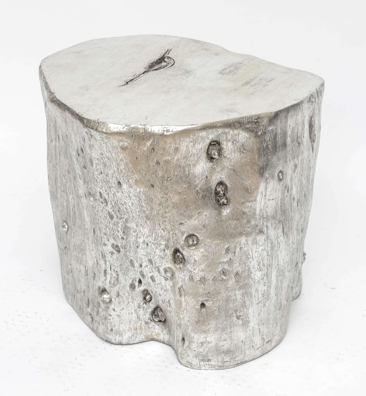 Organic tree trunk-shaped, side or end table, in a silver leaf and platinum patina. Cast fiberglass and weighted, with a flat surfaced top, knots, textures and crevices mimicking a real petrified wood trunk.