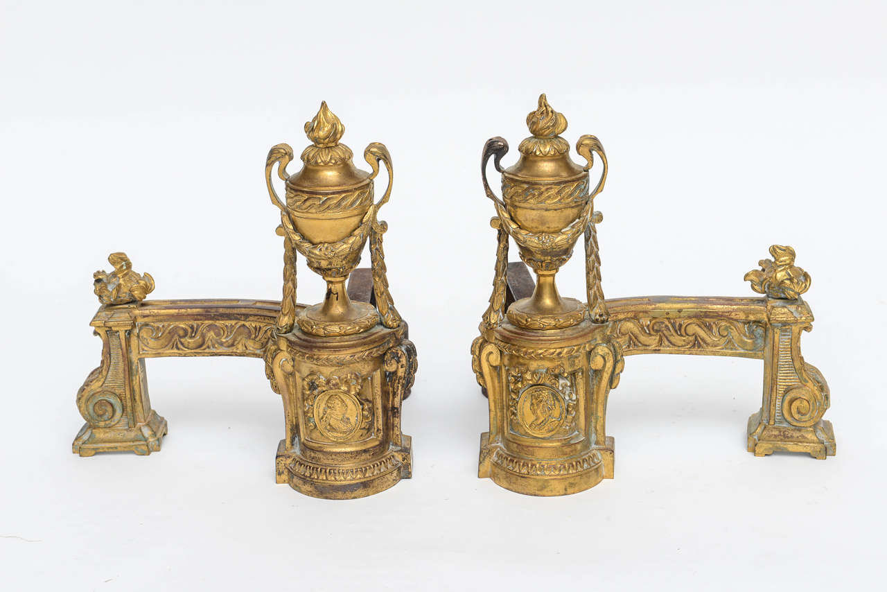 Louis XV gilt bronze chenets. Illustrated with flame finials on top of urns and balustrade. Garland draped with leafage. Original flange support. Featuring images of Louis VI and his wife Marie Leszczyńska the daughter of King Stanislaw I and