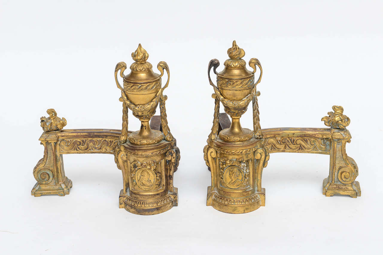 Chenets Louis XV en bronze doré. Illustré par des épis de faîtage à flamme au sommet des urnes et de la balustrade. Guirlande drapée de feuillage. Support de bride d'origine. Avec des images de Louis VI et de son épouse Marie Leszczyńska, la fille