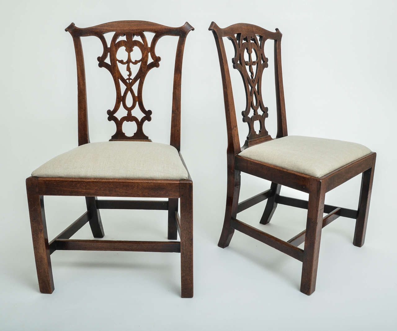 A pair of 18th century George III mahogany side chairs with drop-in seat, pierced splat, and H-stretcher.