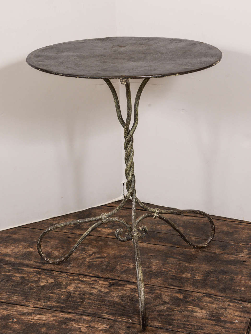 French iron side table, remnants of original paint. A twisted iron base, that is wider than the actual top make this table charming!