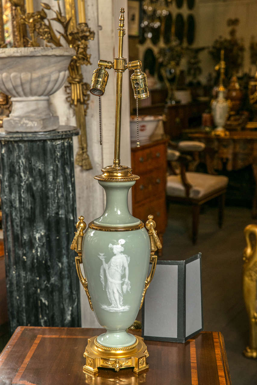A beautiful pair of lamps in celadon with classical figures, in white overlay,
on one side and decorative motif on the other.
Gilt bronze ring handle mounts and base. Height measurement to top of cap is 18 inches.