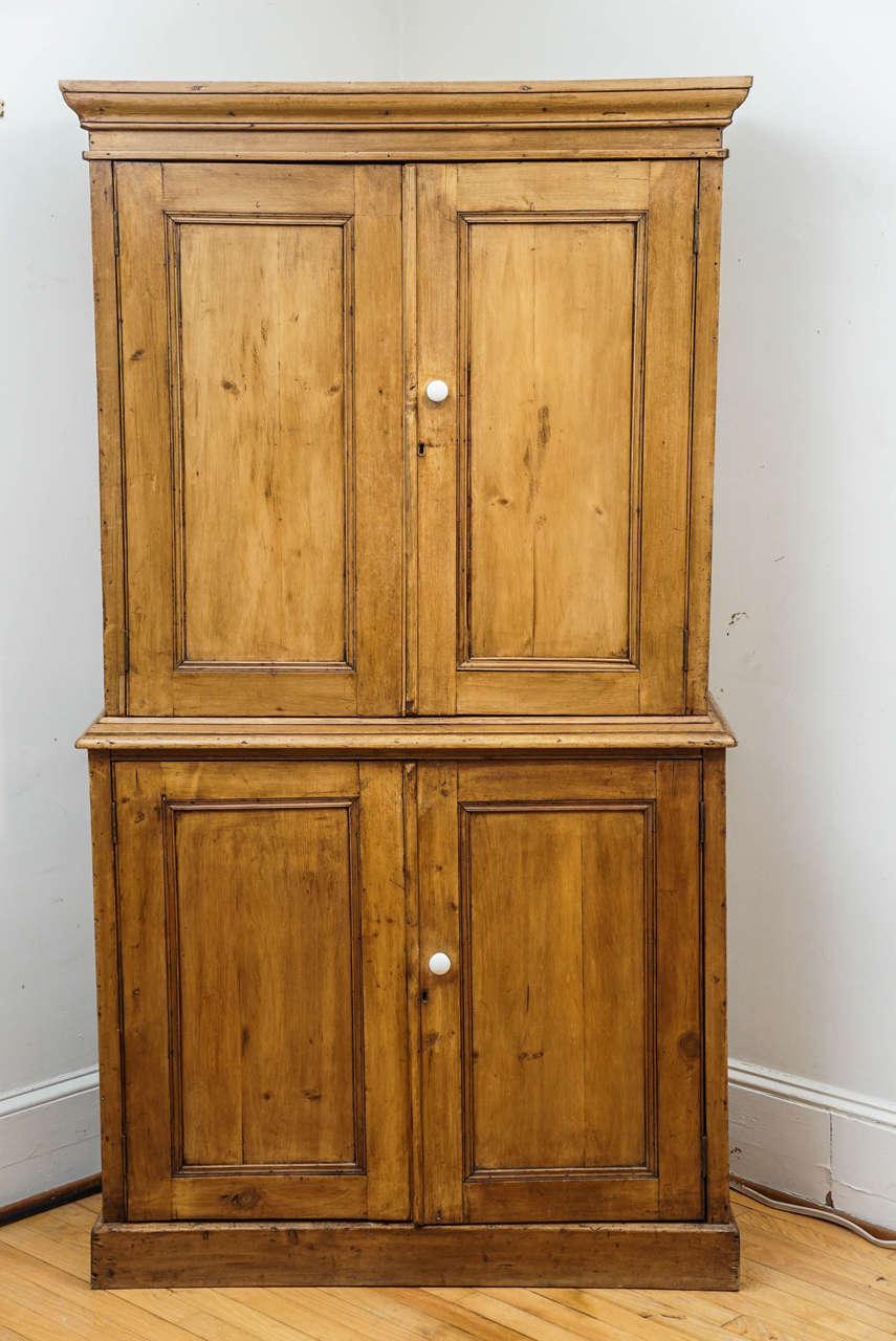 This English four-door cupboard starts with a terrific patina! It is in two pieces. The top has two shelves inside and the bottom has one shelf. The porcelain knobs add much character to the piece. What a terrific piece for your kitchen. We love the