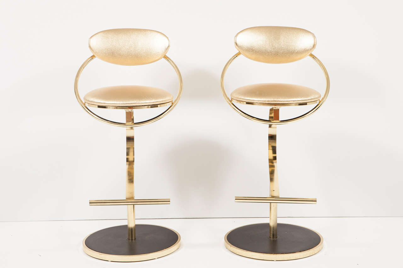 Set of four polished brass barstools featuring new padding and gold leather metallic seats and backs.