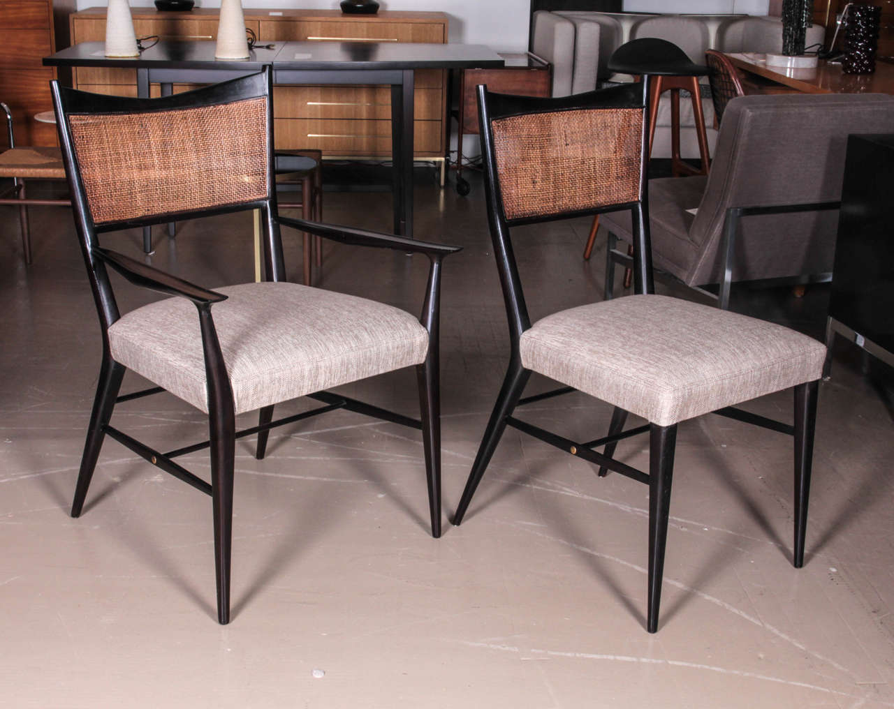 Set of six ebonized Paul McCobb dining chairs with caned backs and linen seats.