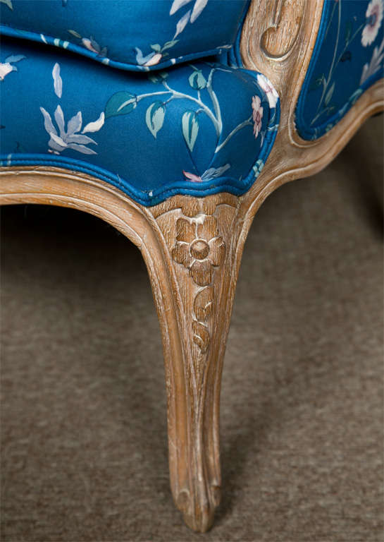French Louis XV style bergere chair, circa 1950s, distressed frame upholstered in blue floral fabric, down swept arm, padded back, cushioned seat, raised on cabriole leg. By Jansen. 
