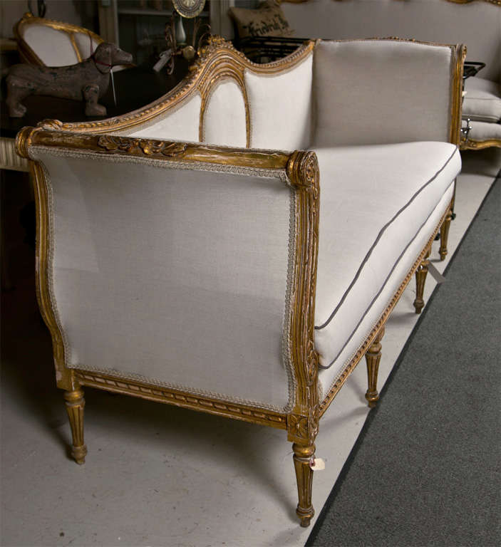 A gorgeous French Louis XVI style giltwood canape sofa, circa 1940s, the lovely carved frame decorated with patera and wreath detail, domed back with an annulated oval medallion pattern in the middle, rolled arms and cushioned seat with newly