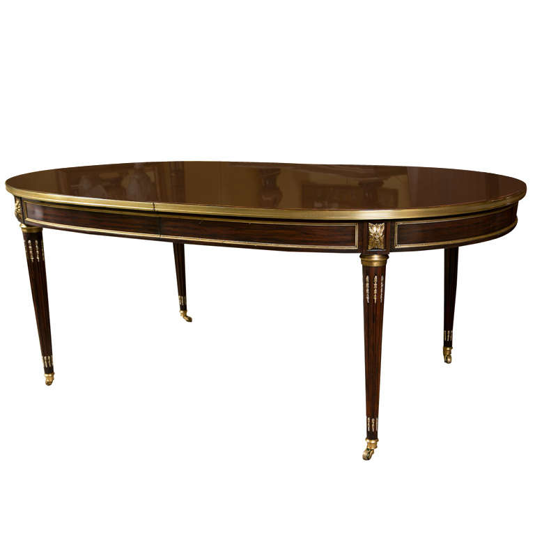 A fine French Louis XVI style oval rosewood dining table, circa 1940s, beautiful rosewood oval top with bronze banding over a narrow frieze decorated with bronze pateras, raised on fluted tapering legs ending in castors. Comes with 3 additional