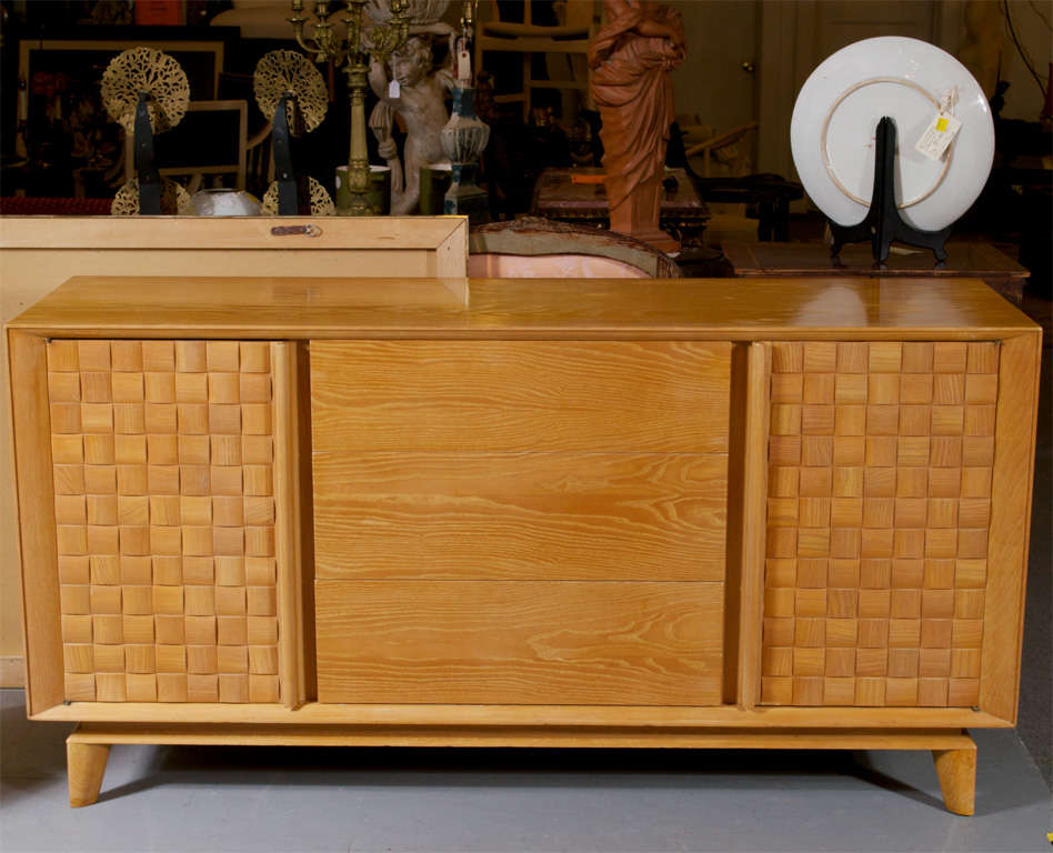 A Paul Laszlo designed basket weave front credenza for Brown Saltman. Has two side cabinets, behind each one is an adjustable shelf. Three drawers with the top drawer having dividers, also has a pull out divided tray in that top drawer for flatware.