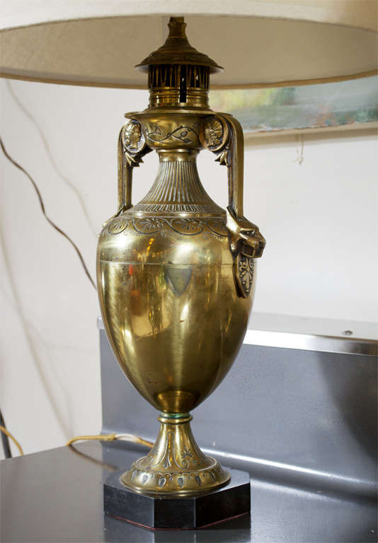 This pair of circa mid to late 19th century neoclassical/egyptian revival oil lamps, have been converted to electircity. They are amphora shaped with curved handels culminating in snarling panther heads. the shoulder features incised leaves. At the