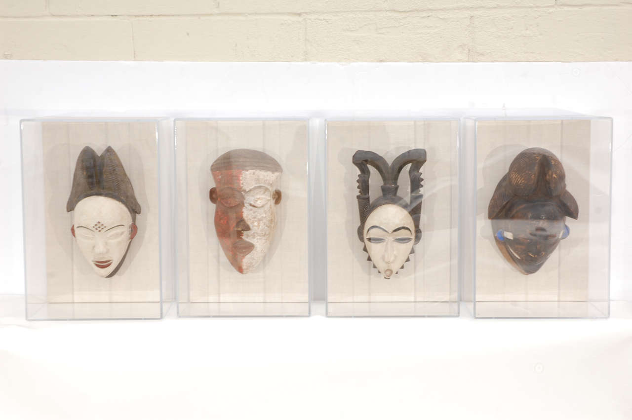 Two sets of African masks from Gabon set in linen backs and Lucite frames. In the main photo, the two center ones have the same size frames. Also, the two outer ones have the same size frames.

Center masks measure 11 1/2
