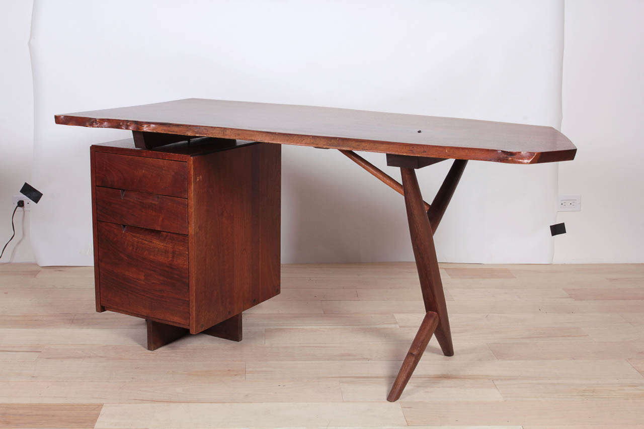 Desk in walnut, Free-edge top, supported by pedestal with three drawers and  crossed leg.  Provenance available.