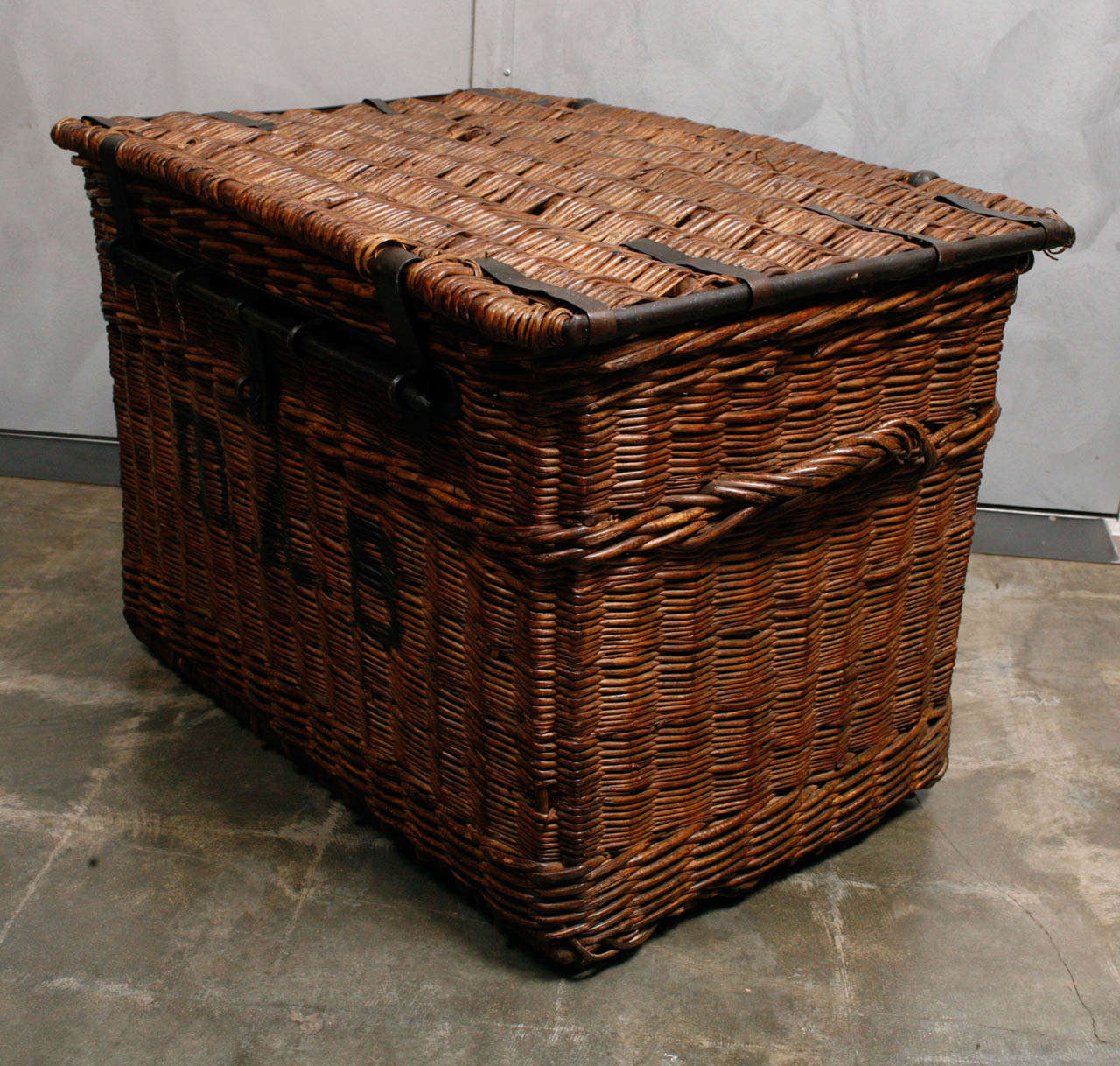 This Wicker trunk is in good condition with some really nice details. The trunk has black lettering painted on the front and Iron fittings, hinges and lock. The trunk is a great size suitable for a variety of uses and has wooden skids at the bottom