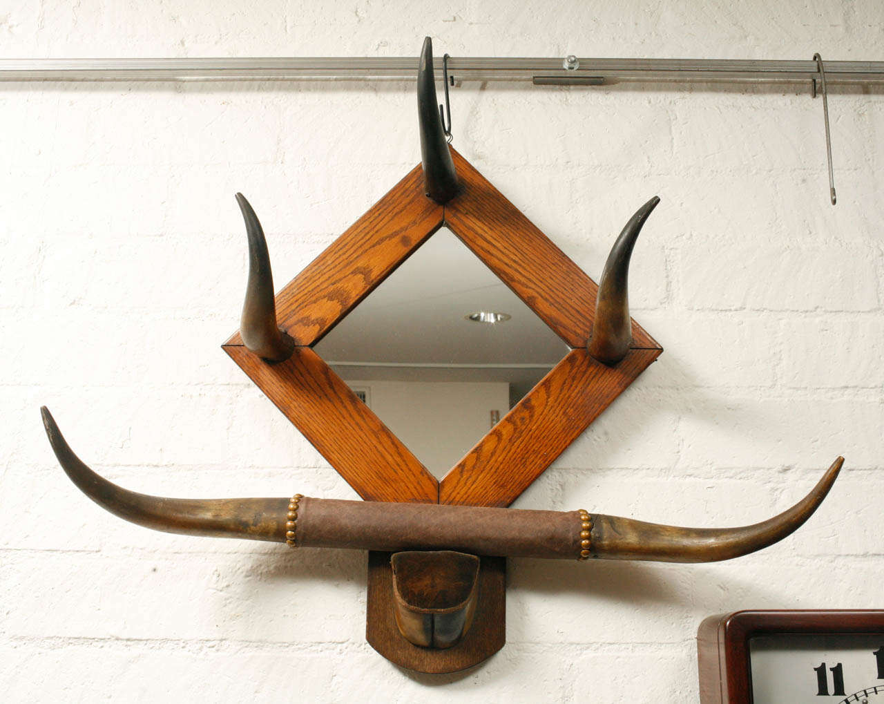 This exceptionally unique horn hat rack with mirror will add utility and interest to a variety of settings. The piece carries the design aesthetics and craftsmanship of an Arts and Crafts era item. Some of its special details include an original