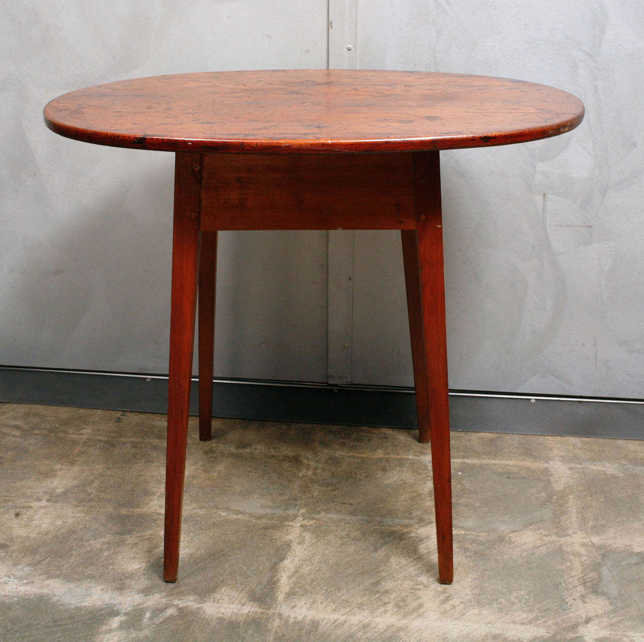 This is a elegant and sturdy little American tavern table with a nicely proportioned table skirt, four tapered legs and a distressed top. The embedded markings and scratches on the table top are signs of heavy use. The table has been cleaned and