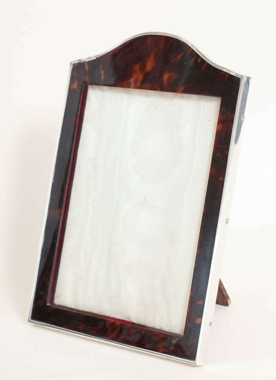 Arched faux tortoiseshell frame with sterling silver border. Original leather back and oak stand.
Hallmarks: 925 silver/ London/ 1917/ CD

Variety of Art Deco period frames available.