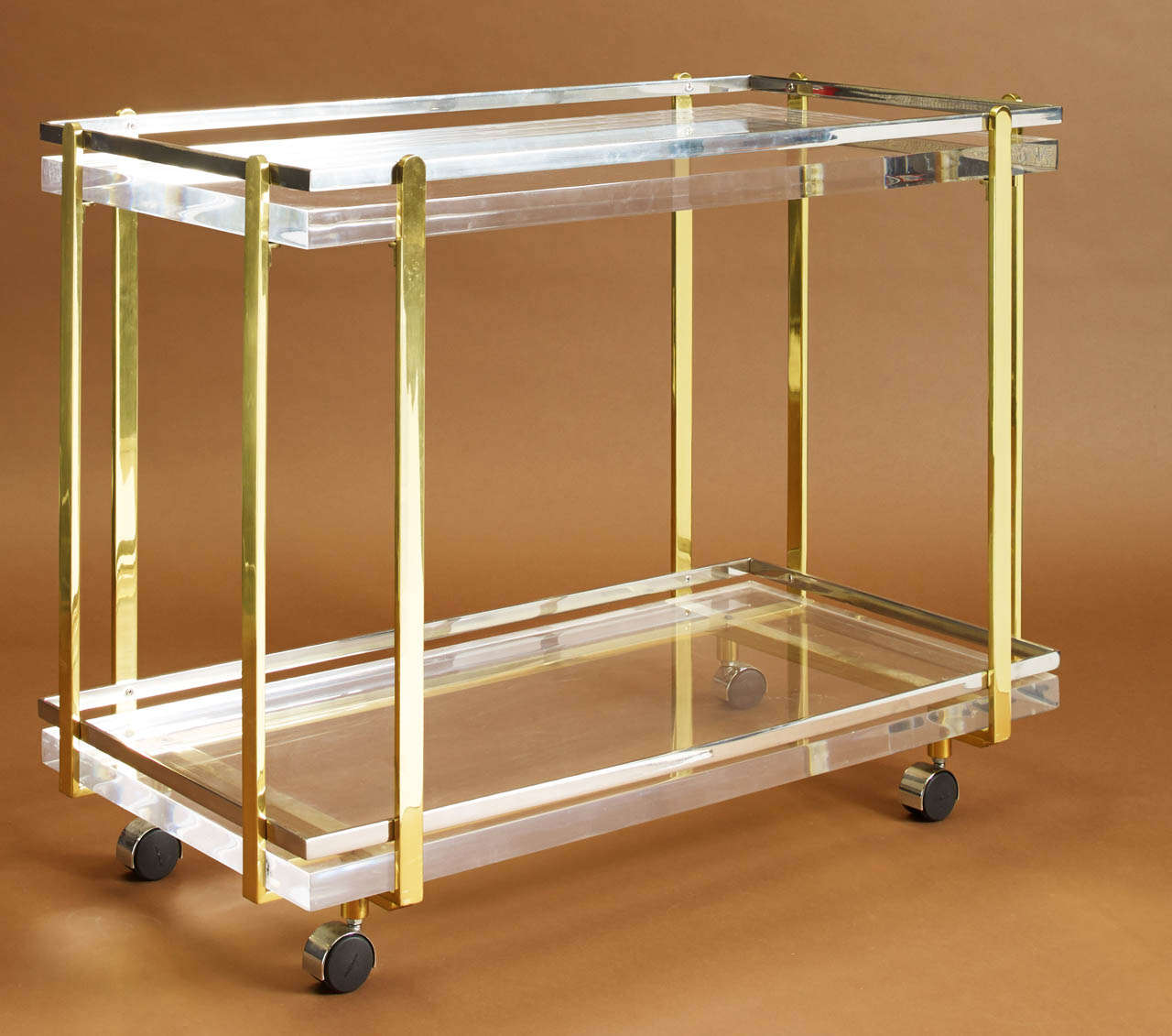 KARL SPRINGER (1930-1991)
Mixed metal framed bar cart in brass and chrome on casters with two lucite shelves
American, c. 1965